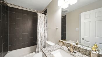 A bathroom with a white tub, sink, and shower curtain.